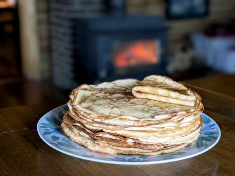 A warm stack of homemade pancakes on a plate, set against a cozy fireplace in Truro, NS, Canada.
